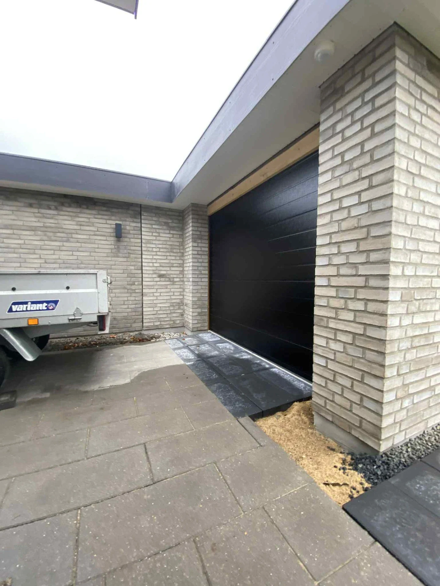 Ny garage med sort port og murværk af teglsten.