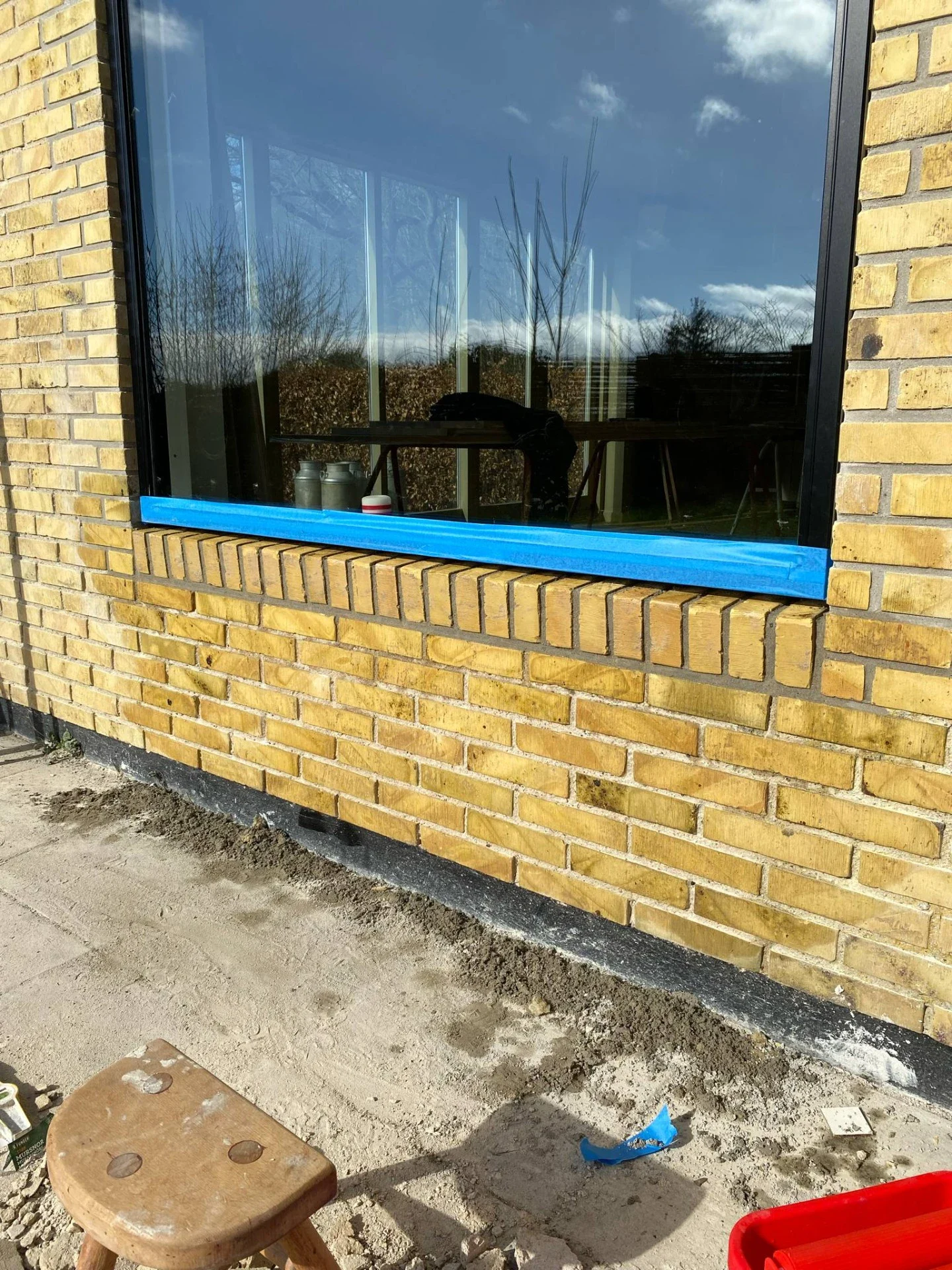Nyrenoveret murervindue med blå kant på gulstensfacade.
