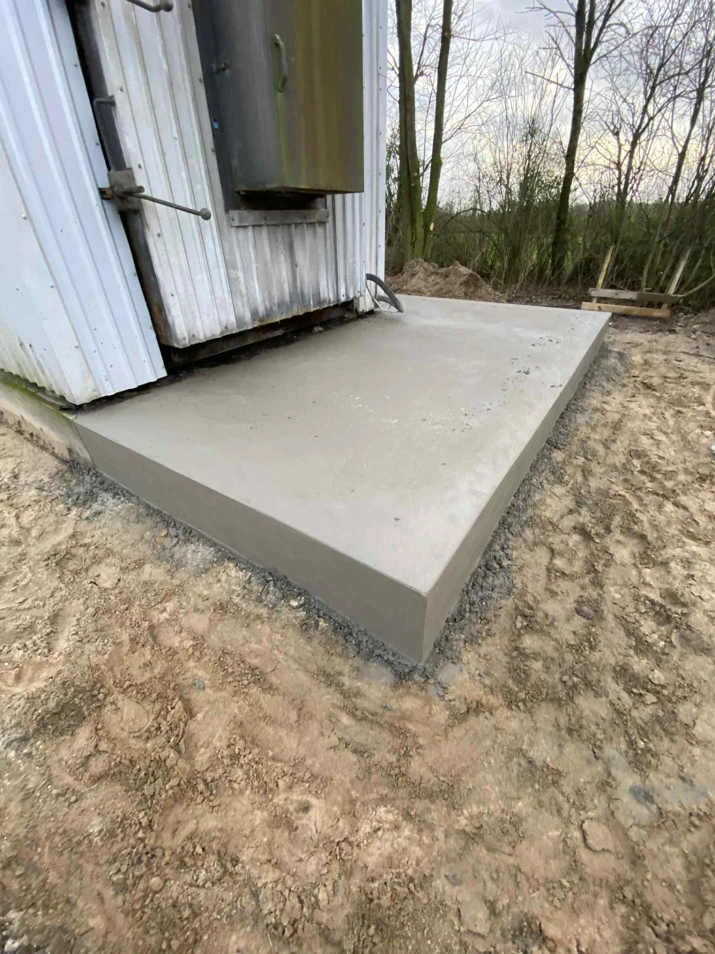 Nyt betonfundament foran en bygning, klar til installation.