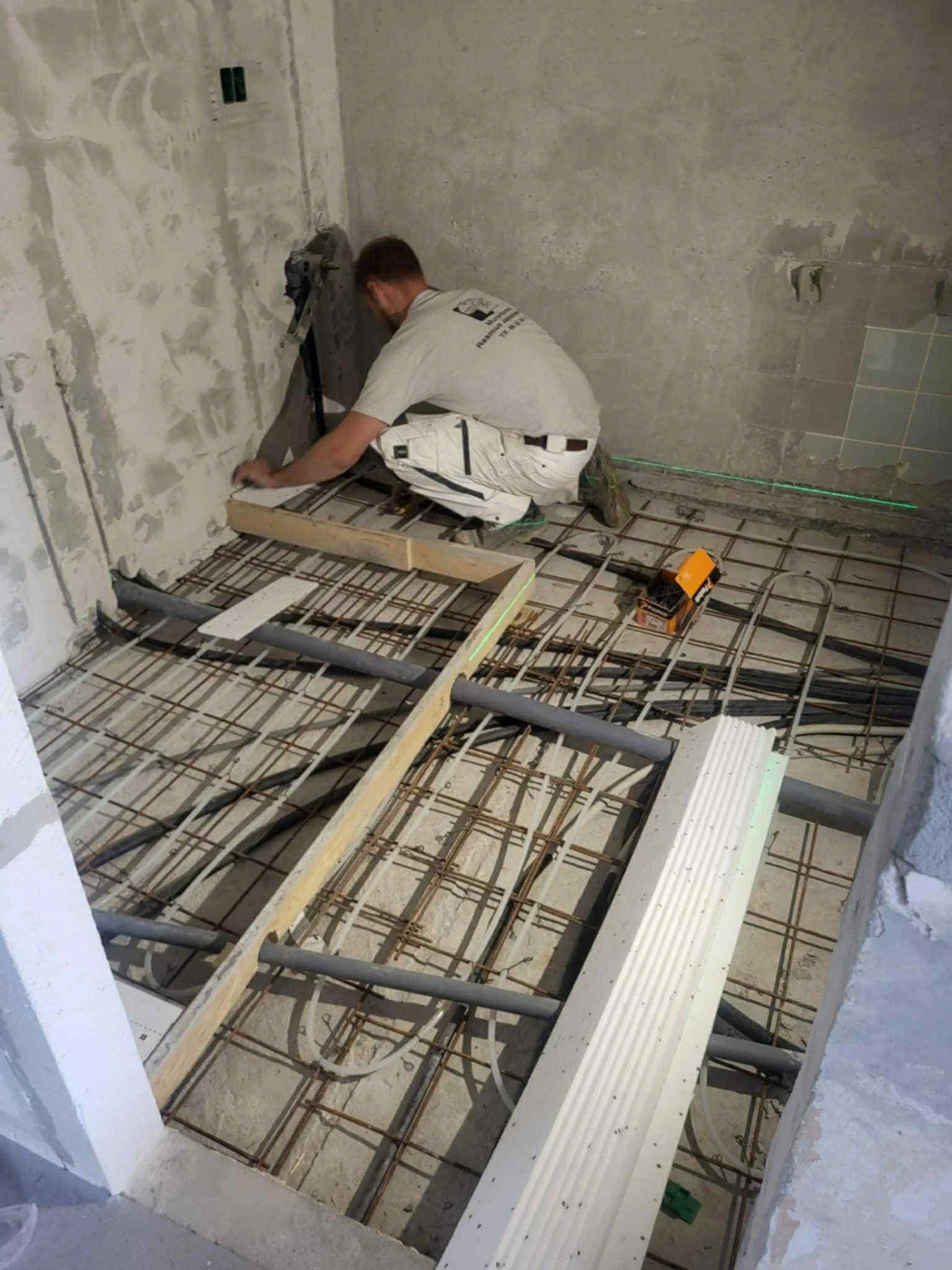 Murer arbejder på installation af gulvvarmesystem i nybyggeri.