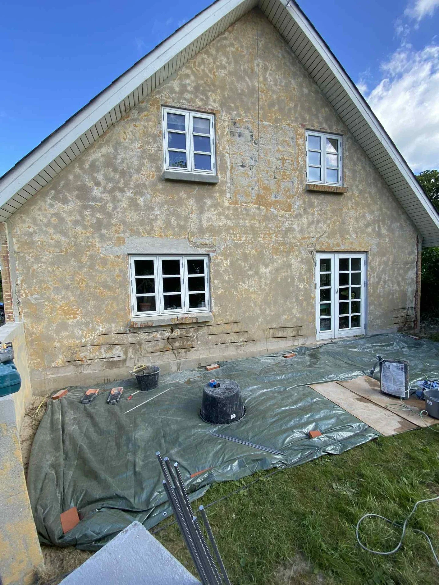Udendørs husfacade renovering med nye vinduer og dør.